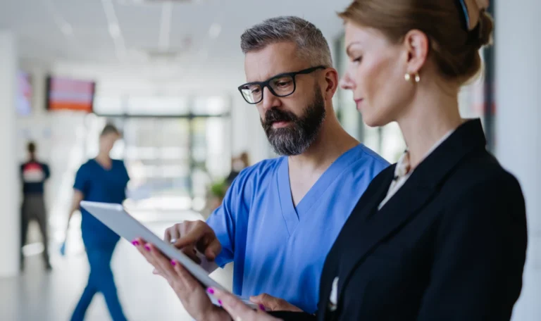 Healthcare professionals reviewing purchasing and operational data on a tablet inside a healthcare facility.