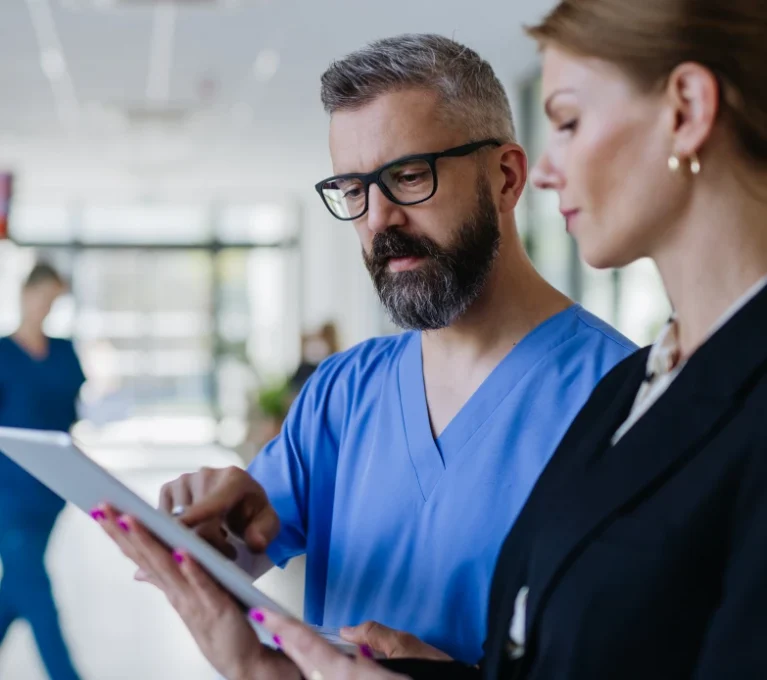 Healthcare professionals reviewing purchasing and operational data on a tablet inside a healthcare facility.